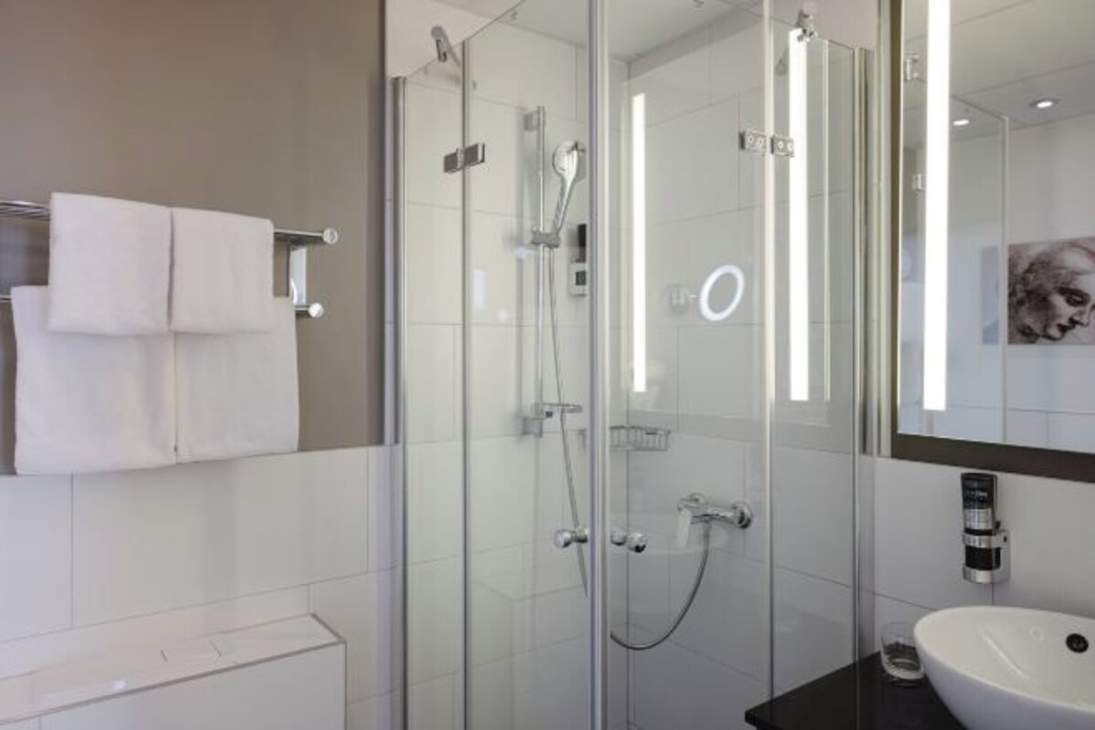 Un baño moderno con cabina de ducha de vidrio, un lavabo blanco y un perchero para toallas.