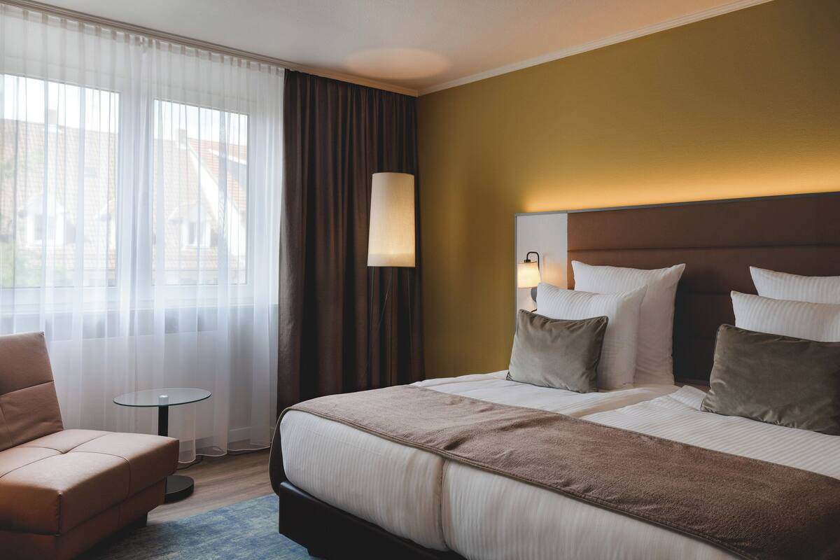 Une chambre d’hôtel avec un lit, une chaise, une petite table et une lampe.