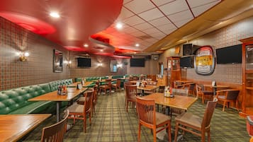 A restaurant interior with booths, tables, and a patterned carpet.