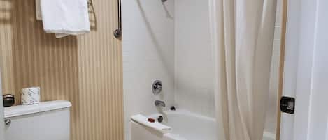A bathroom with a toilet, a shower with a curtain, and a towel rack with towels.