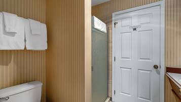 A bathroom with a toilet, a towel rack with towels, and a door.