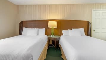 A hotel room with two single beds, a nightstand with a lamp, and a door.