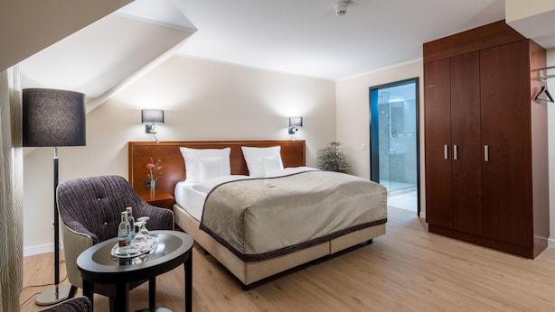 A modern hotel room with a bed, bedside tables, a chair, a small table with a tray, and a wardrobe. - Best Western Plus Hotel Excelsior (Erfurt)