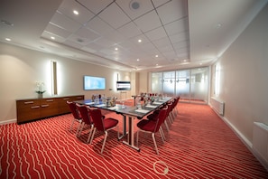A conference room with a long table, red chairs, a television screen, and a digital display on the wall. - Best Western Plus Hotel Excelsior (Erfurt)