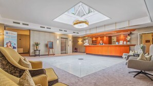 A hotel lobby with a reception desk, seating area, and a skylight. - Best Western Plus Hotel Excelsior (Erfurt)