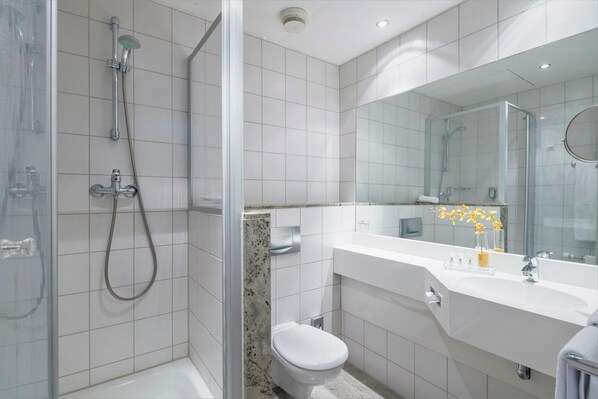 A modern bathroom with a glass-enclosed shower, a white toilet, and a vanity with a mirror.