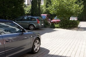A parking area with multiple cars, a paved surface, and surrounding greenery.