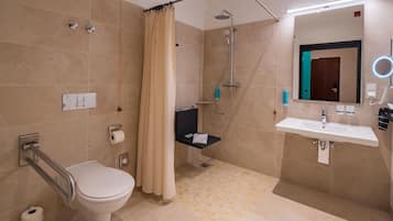 Un baño moderno con inodoro, ducha, lavabo y un espejo con luz.