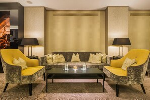 Una sala de estar moderna con un sofá, dos sillones, una mesita de centro y una alfombra estampada.