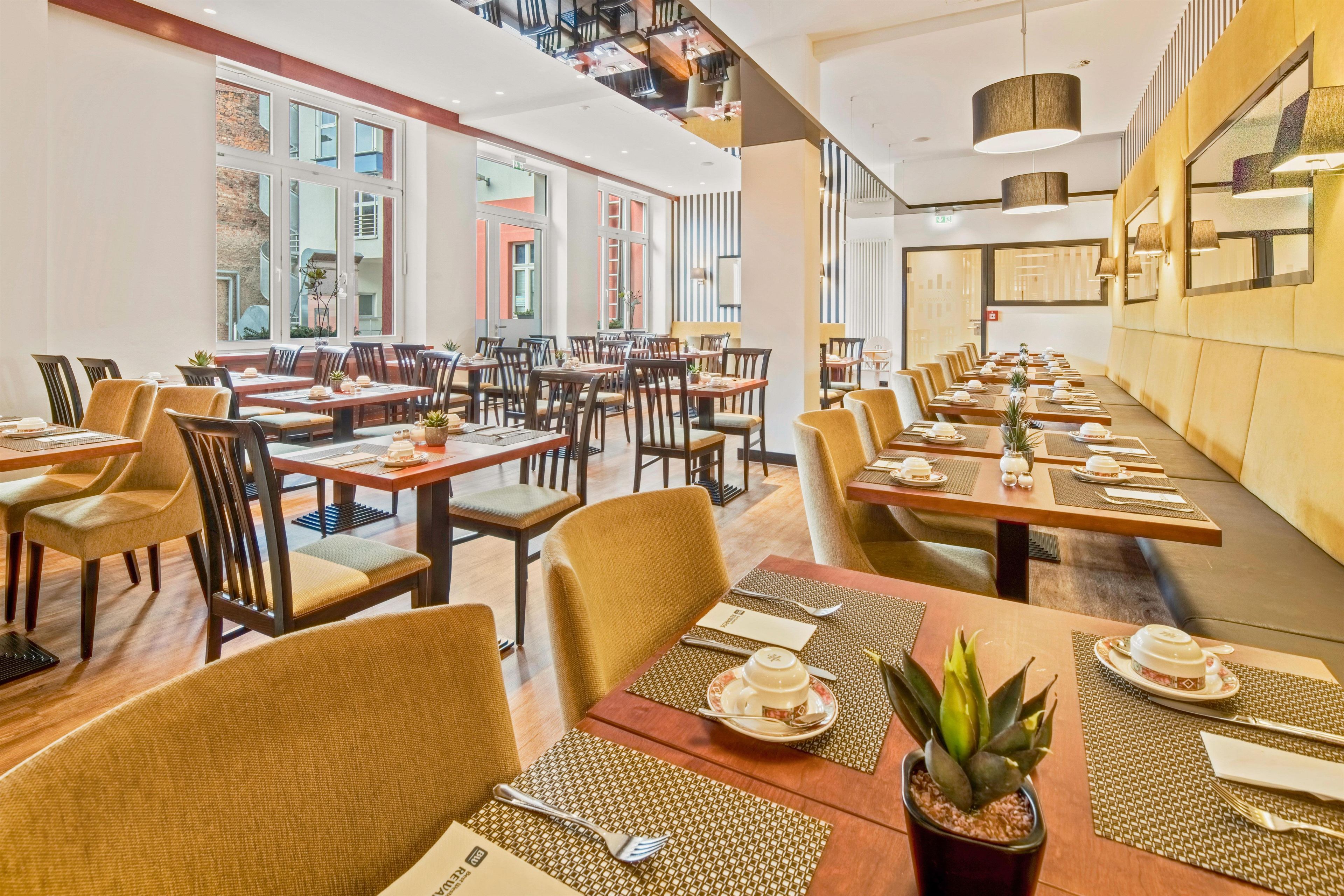 Un restaurante con varias mesas y sillas, amplias ventanas y una decoración interior moderna.