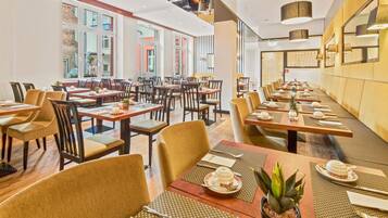 Un restaurante con varias mesas y sillas, amplias ventanas y una decoración interior moderna.