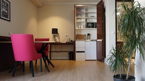 A compact kitchen with a microwave, a small refrigerator, and a dining area with a red chair. - Best Western Plus Hotel Excelsior (Erfurt)