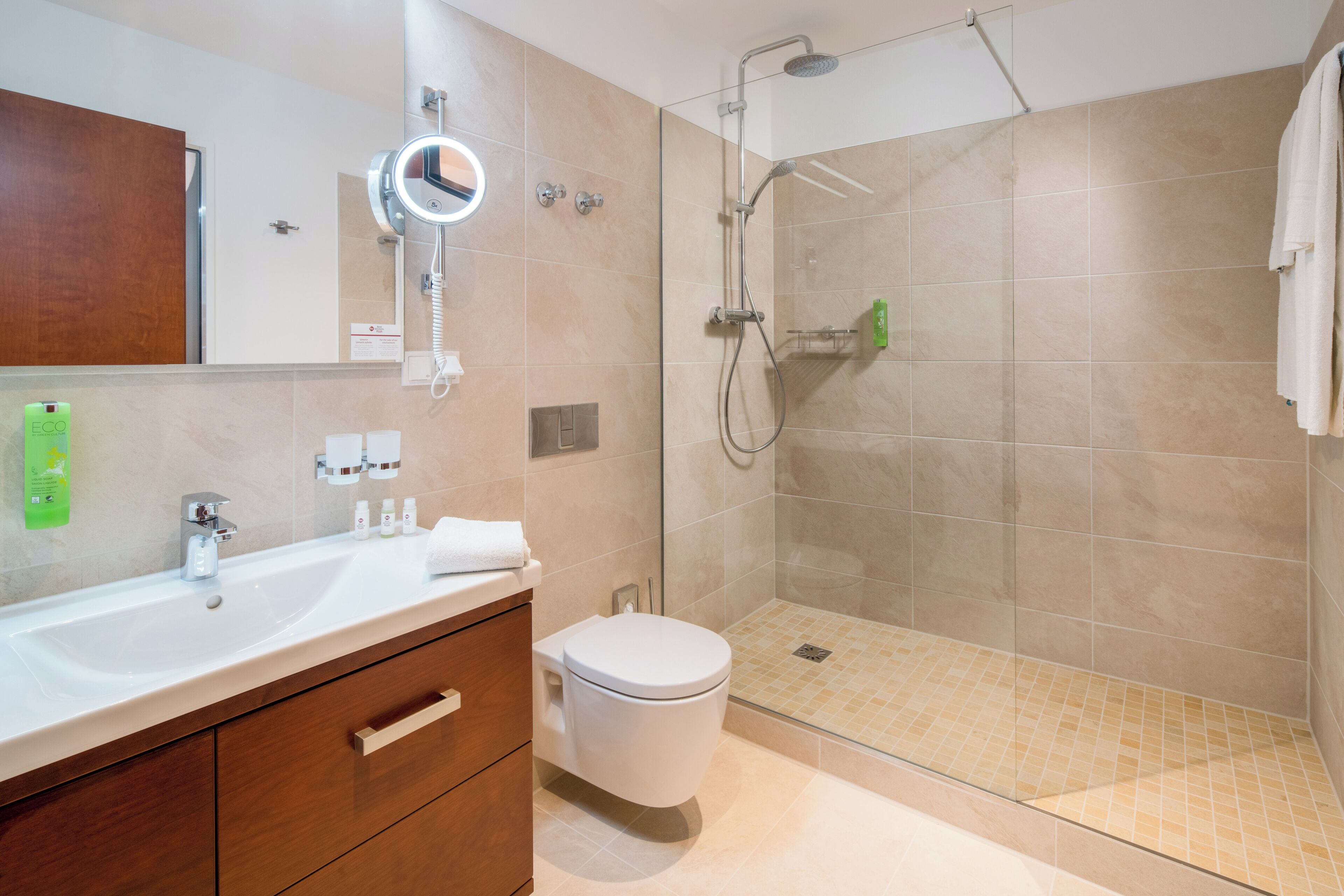 A modern bathroom with a shower, toilet, and sink.