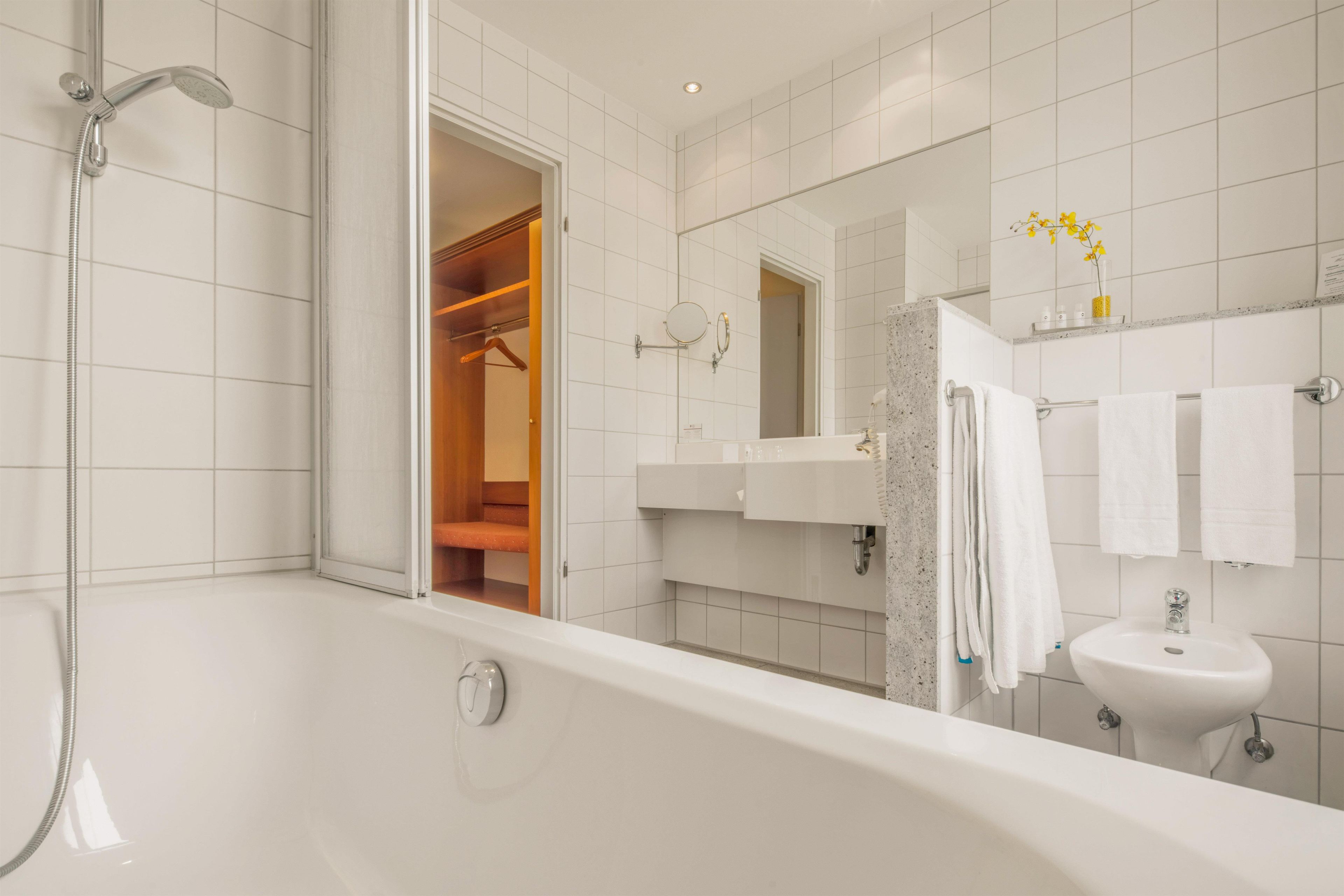 Un baño moderno con bañera, ducha, lavabo y espejo.