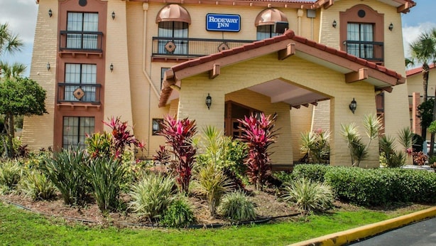 Un Rodeway Inn de dos pisos, con un acceso cubierto y un jardín ajardinado con diversas plantas.
