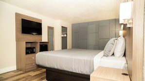 Un dormitorio con una cama, un televisor en la pared, un microondas y un armario.