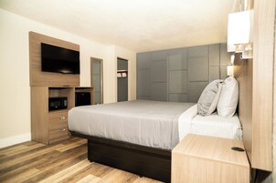 Un dormitorio con una cama, un televisor en la pared, un microondas y un armario.