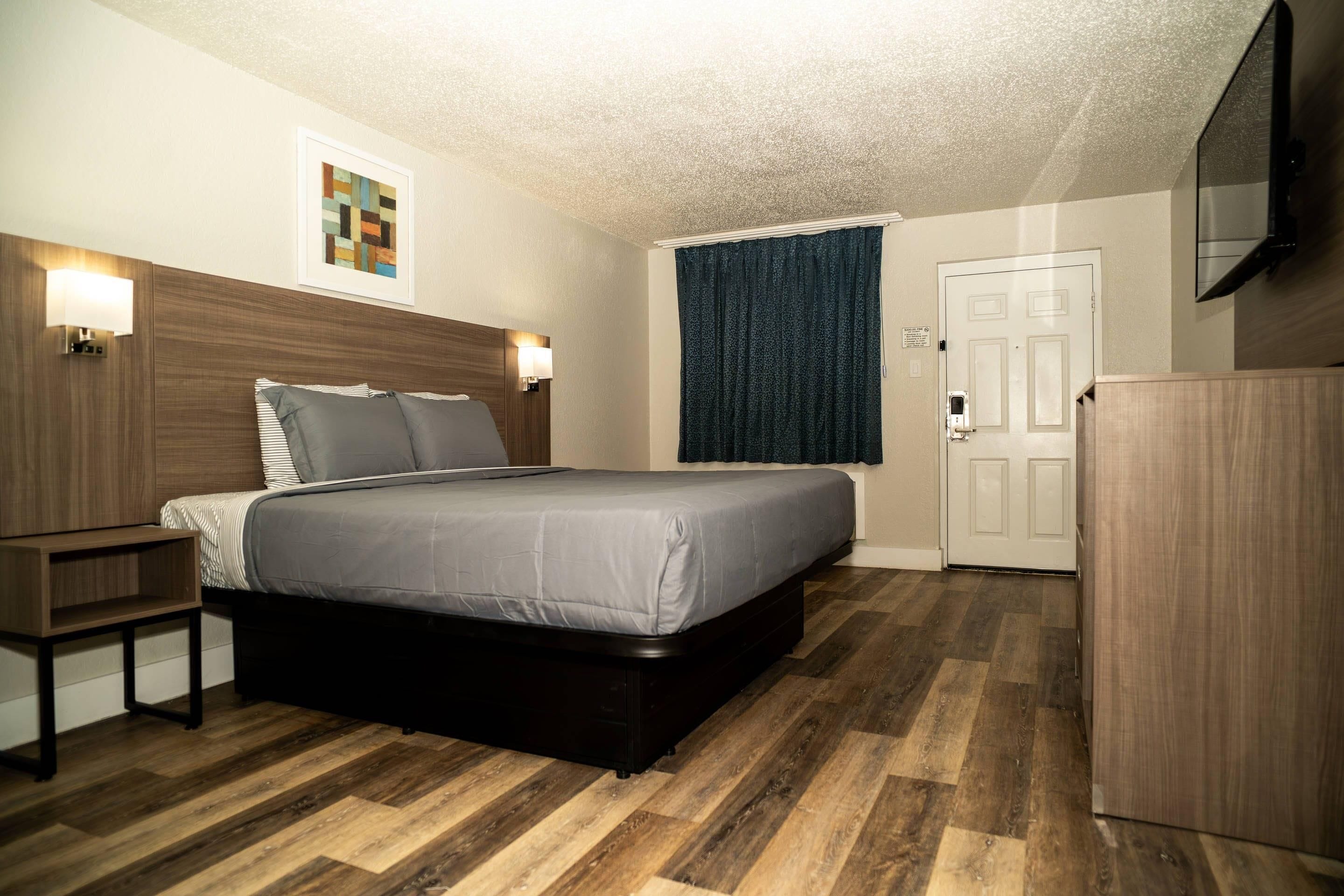 A hotel room with a bed, a nightstand, a wardrobe, and a wall-mounted TV.