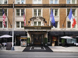 A hotel entrance with a black awning, a sign reading "THE MARK", and flags of the USA, France, and Italy.
