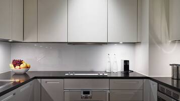 A modern kitchen with stainless steel appliances, a black countertop, and a bowl of fruit.