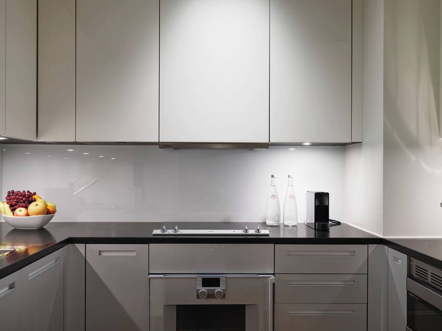 A modern kitchen with stainless steel appliances, a black countertop, and a bowl of fruit.
