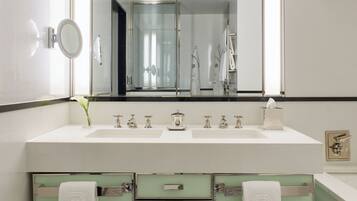 A modern bathroom with a large mirror, two sinks, a green vanity, and a towel rack.
