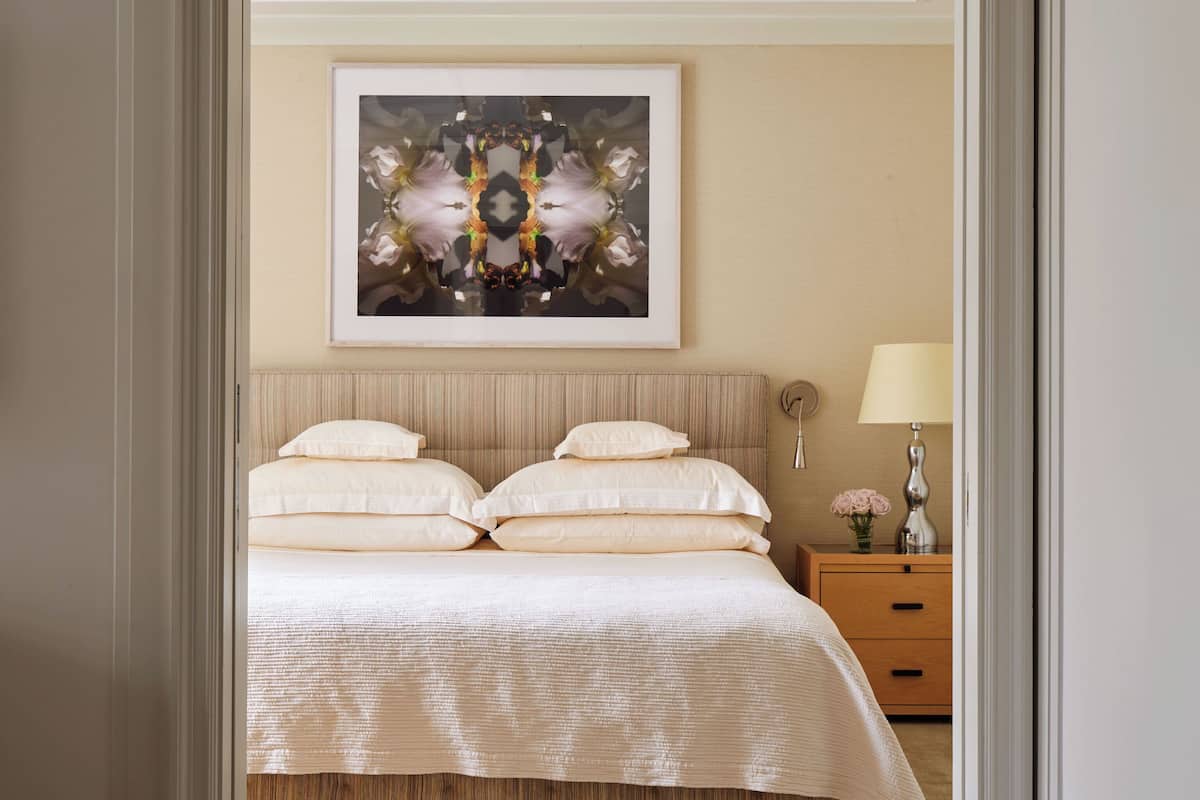 A bedroom with a bed, a nightstand, a lamp, and a framed artwork on the wall.