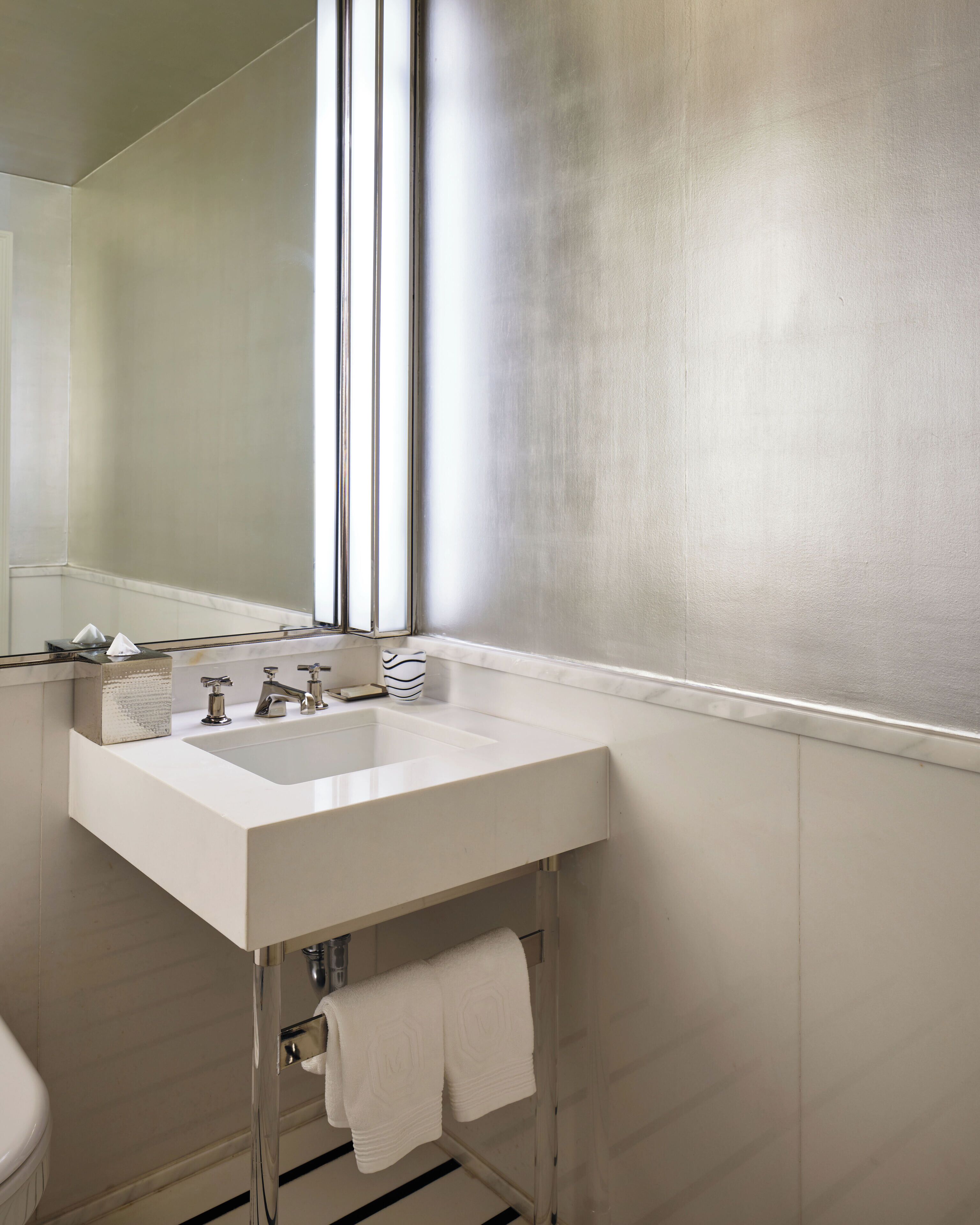 Une salle de bain avec un lavabo blanc, un miroir et un porte-serviettes.