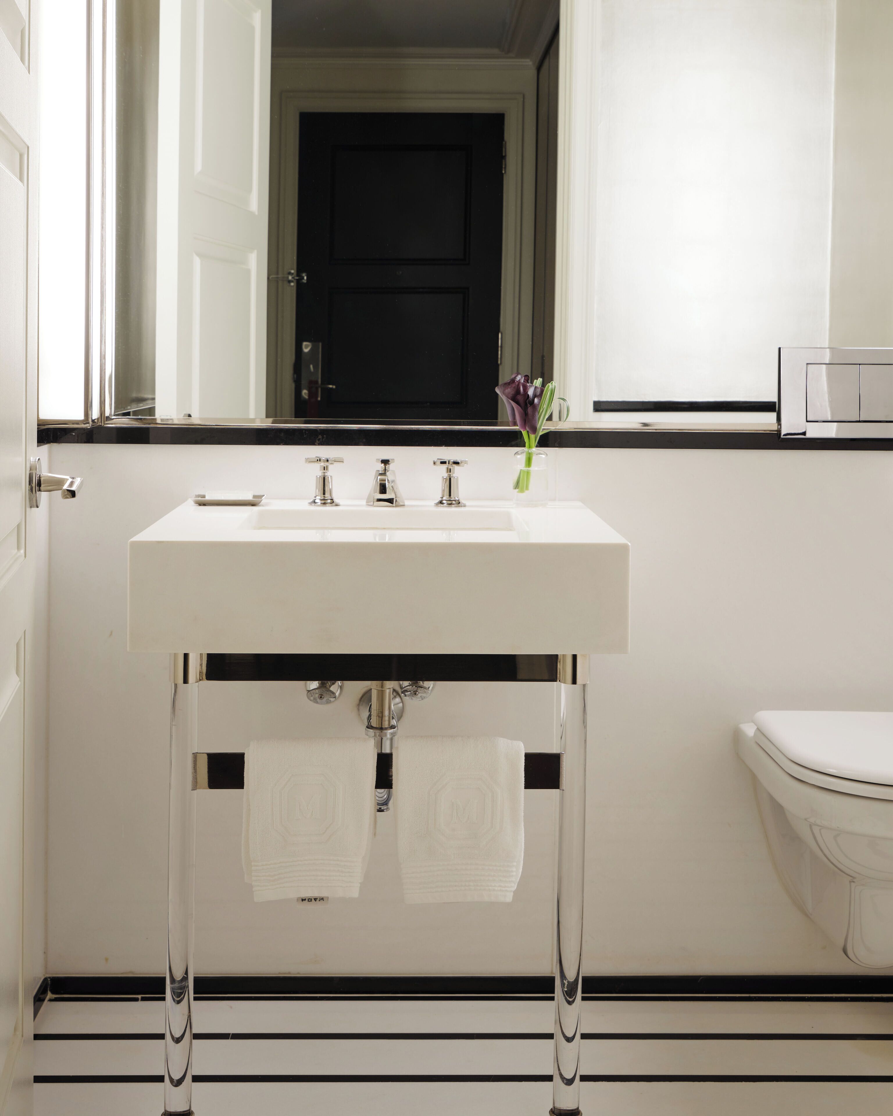 A modern bathroom with a white sink, three faucets, and a toilet.