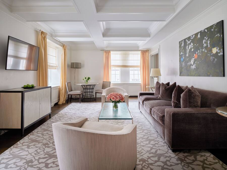 En moderne stue med sofa, lænestol og sofabord. Der er et TV monteret på væggen, en lampe og et billede.