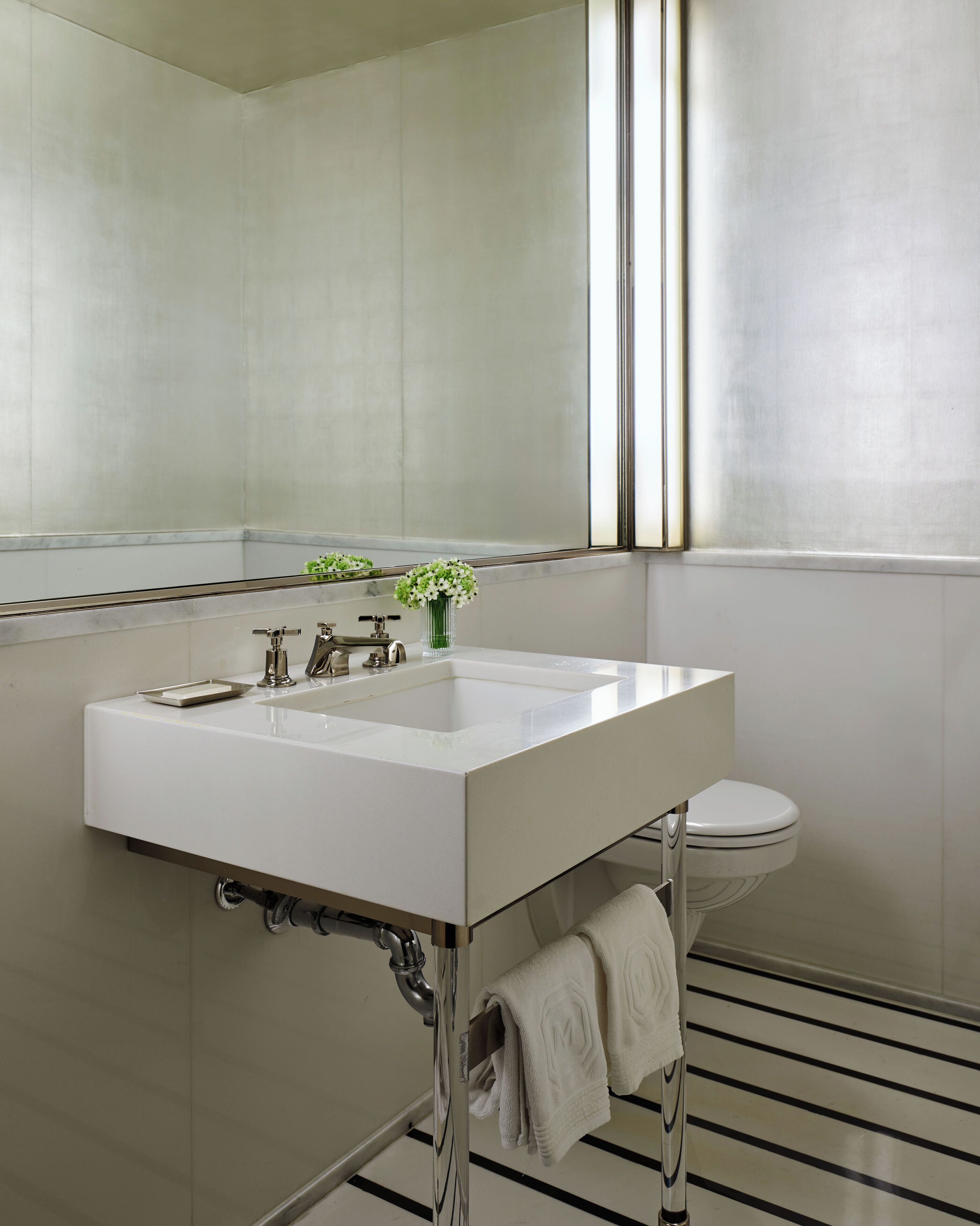 A modern bathroom with a white sink, chrome fixtures, a mirror, and a toilet.