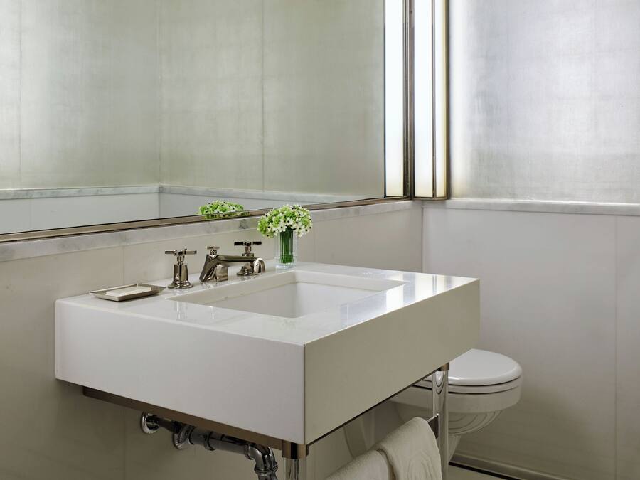 A modern bathroom with a white sink, chrome fixtures, a mirror, and a toilet.