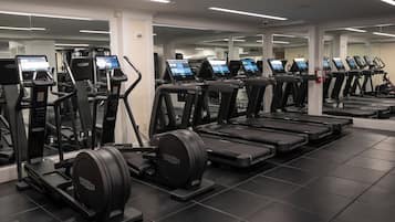 A gym with multiple treadmills and elliptical machines, each with a digital display.