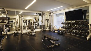 Un gimnasio con equipo de ejercicio, una banca y una barra de mancuernas.