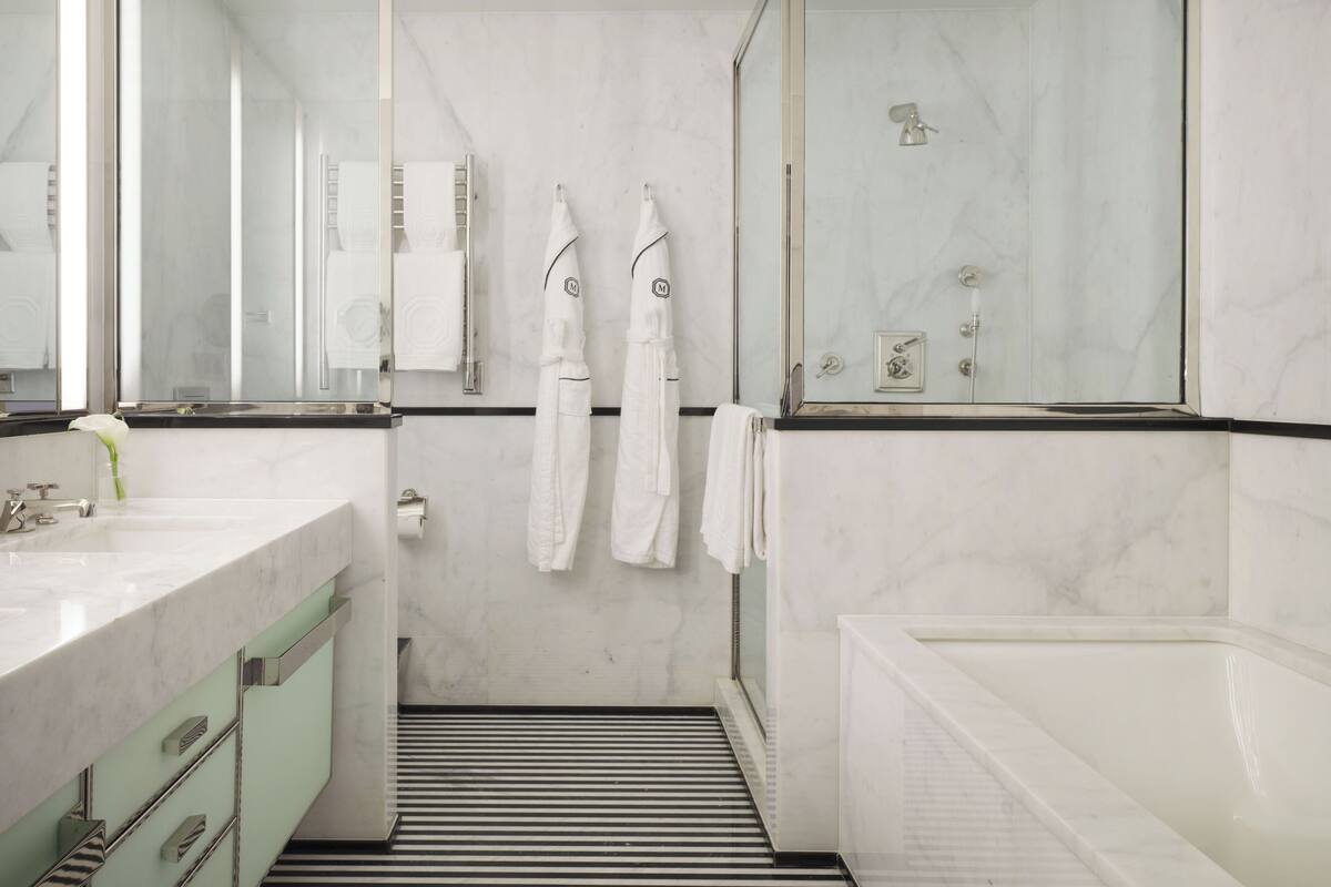 A modern bathroom with a large mirror, a bathtub, and a shower area.