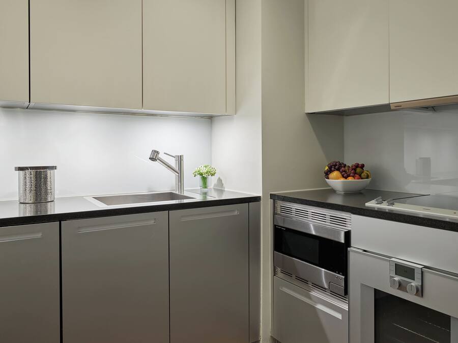 Una cucina moderna con elettrodomestici in acciaio inossidabile, un piano di lavoro nero e una ciotola di frutta sul bancone.