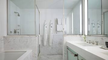A modern bathroom with a bathtub, two sinks, and a shower.