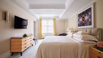 A hotel room with a large bed, a TV mounted on the wall, a dresser, and a window with curtains.