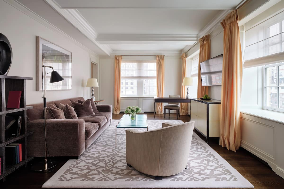 A modern living room with a sofa, armchair, and coffee table, a TV, and a bookshelf.