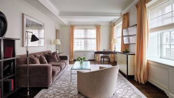 A modern living room with a sofa, armchair, and coffee table, a TV, and a bookshelf.