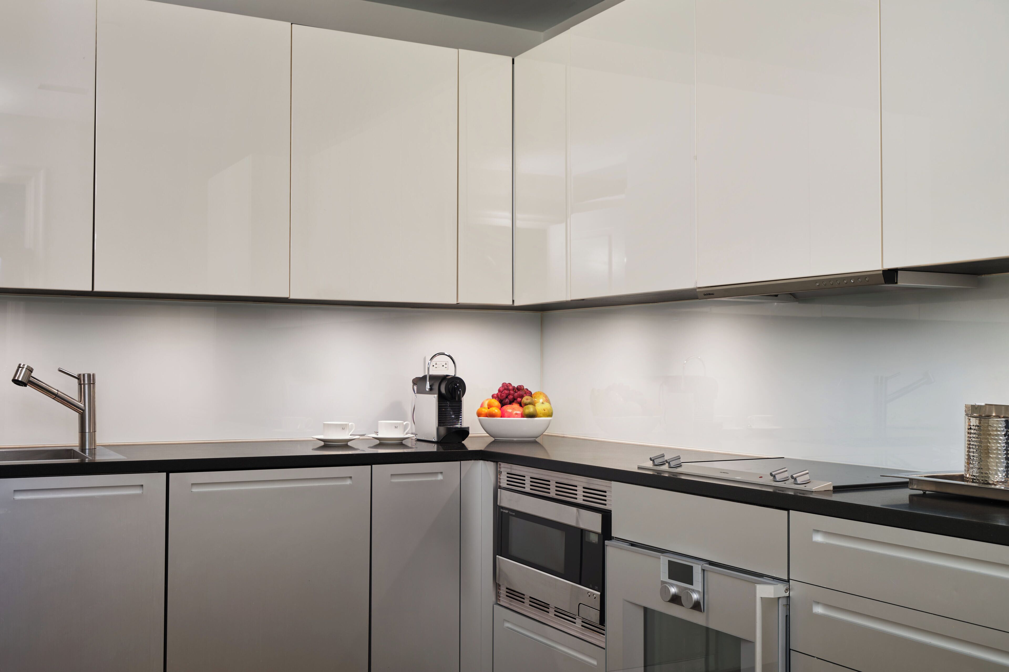 A modern kitchen with white cabinets, stainless steel appliances, and a black countertop.