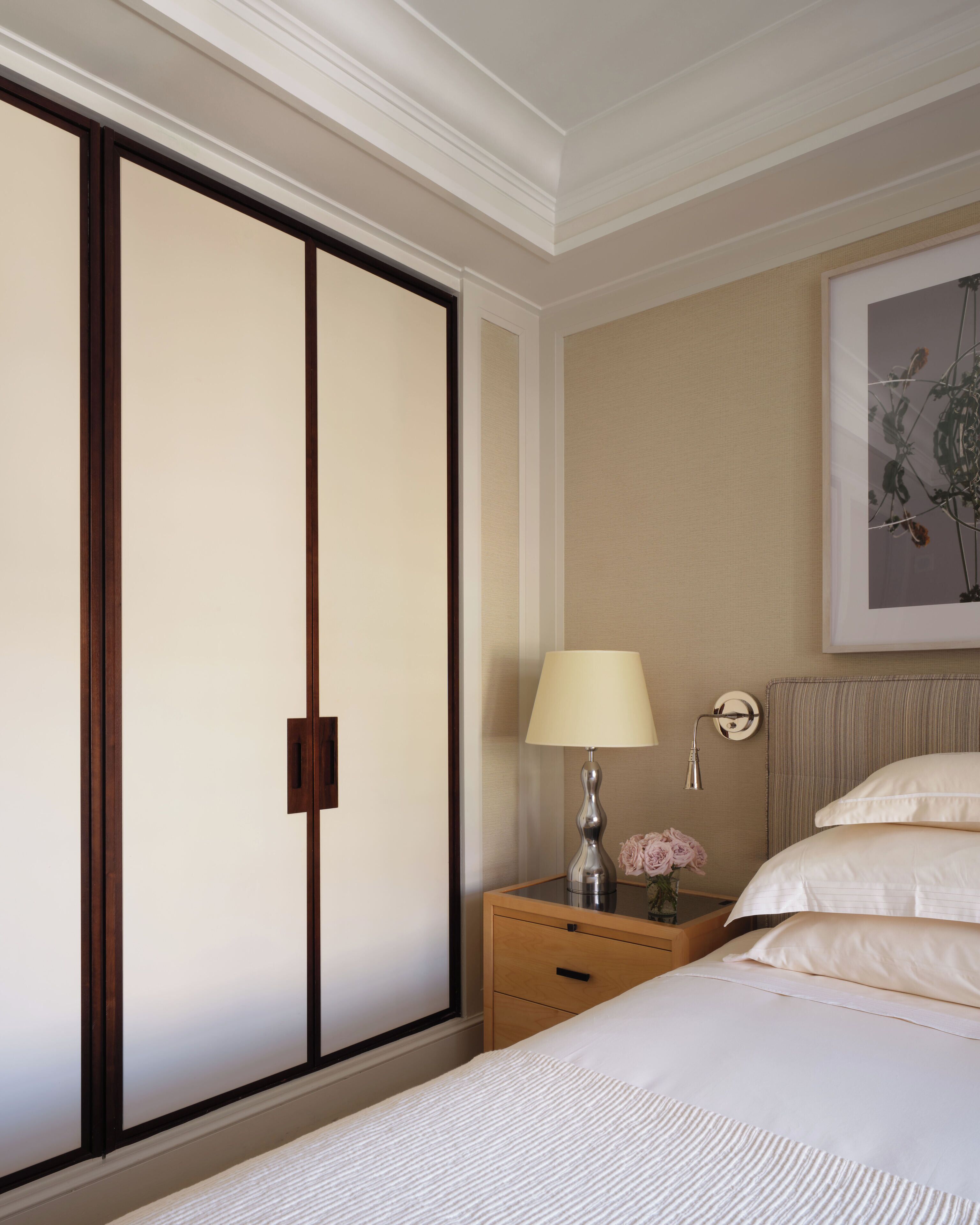 A hotel room with a bed, a nightstand, a lamp, a framed artwork, and a sliding door.
