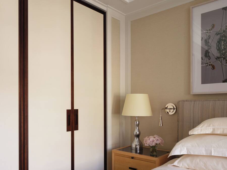 A hotel room with a bed, a nightstand, a lamp, a framed artwork, and a sliding door.