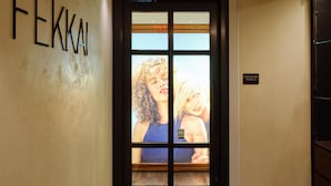 Entrada de un hotel con una puerta negra, una placa con el nombre 