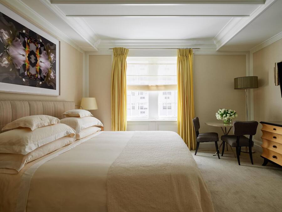 Een hotelkamer met een groot bed, een bureau met lamp, een stoel en een televisie aan de muur.