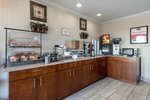 Una barra de desayuno con pan, máquinas de café y un letrero que anuncia desayuno continental.