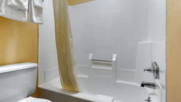 A bathroom with a white bathtub, a toilet, and a towel rack with towels.