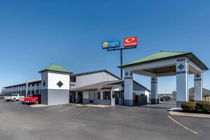 Un Comfort Inn y un EconoLodge con una gasolinera, estacionamiento y un edificio con techo verde.