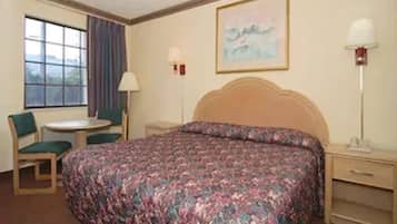 Habitación de hotel con una cama grande, un escritorio, una silla, una ventana con cortinas y un cuadro en la pared.