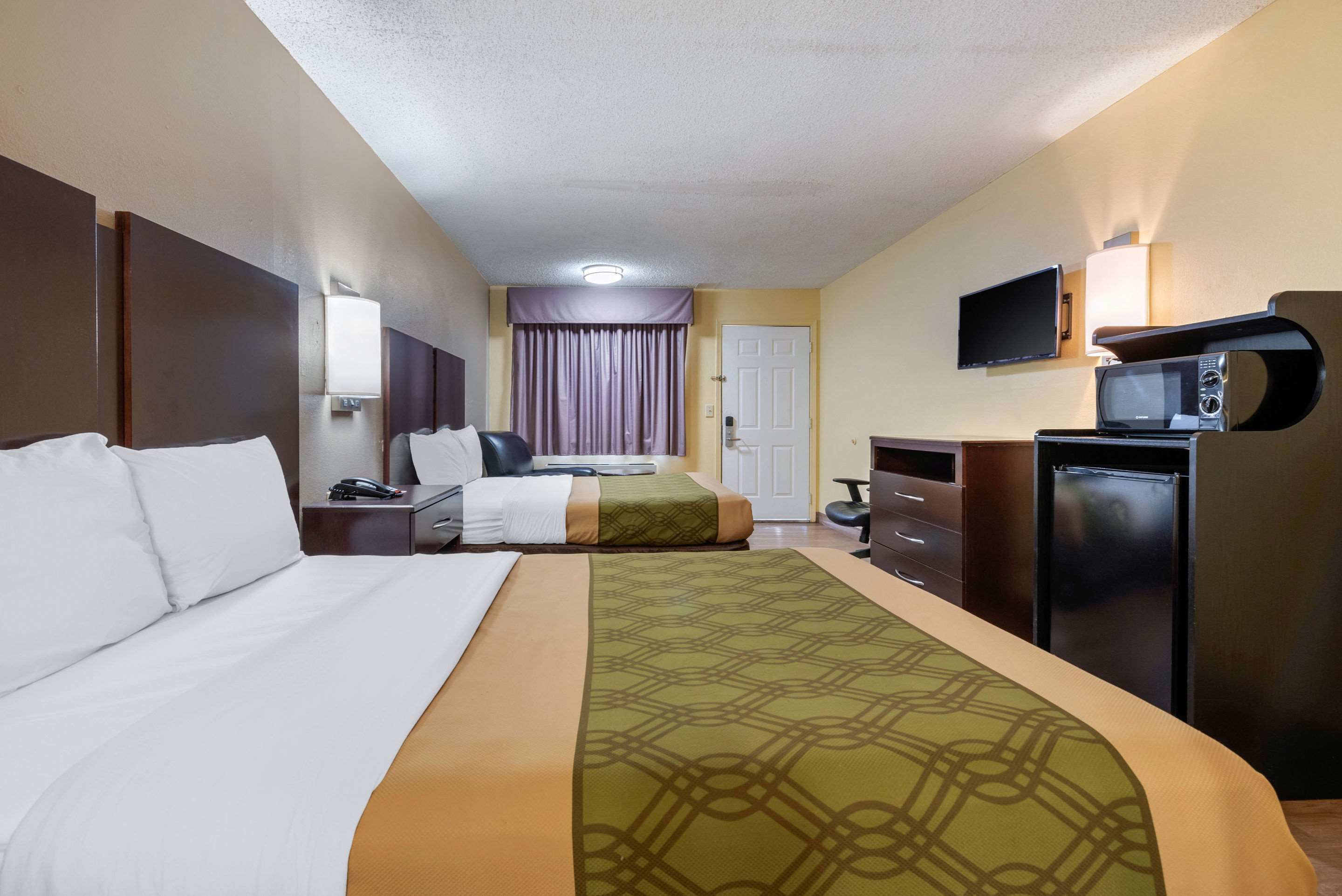 A hotel room with a large bed, a desk with a computer, a microwave, and a television.